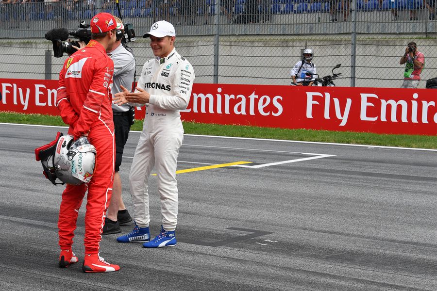 pole sitter Valtteri Bottas talks with Sebastian Vettel on the grid