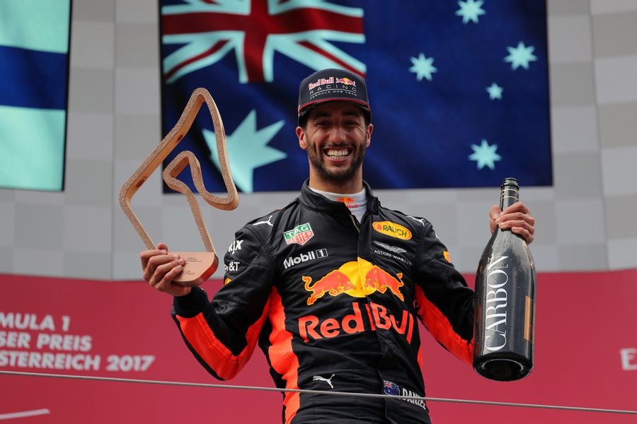 Daniel Ricciardo celebrates on the podium with the trophy and the champagne