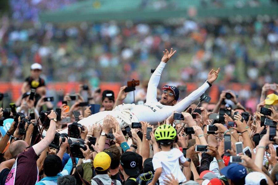 Race winner Lewis Hamilton celebrates with the fans and crowdsurfs