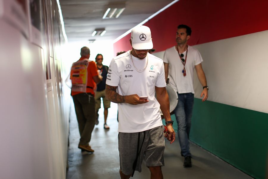 Lewis Hamilton checks his phone in the paddock