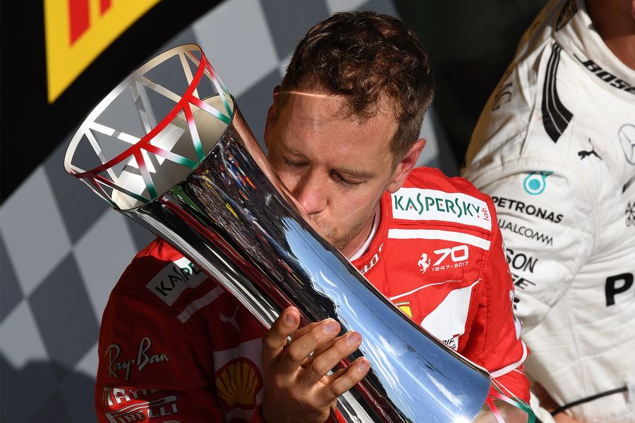 Race winner Sebastian Vettel celebrates on the podium and kisses the trophy