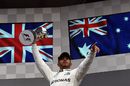 Lewis Hamilton celebrates on the podium with the trophy