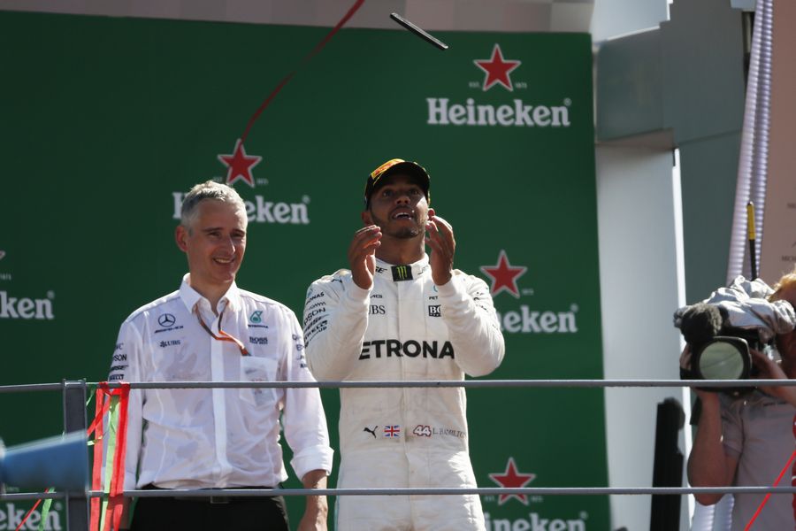 Race winner Lewis Hamilton celebrates on the podium with the his mobile phone