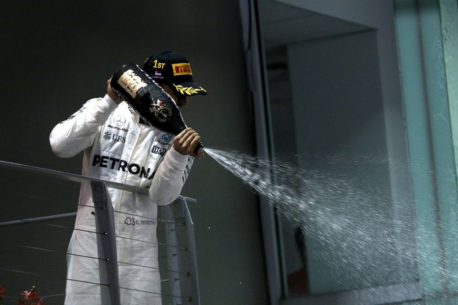 Race winner Lewis Hamilton celebrates on the podium with the champagne
