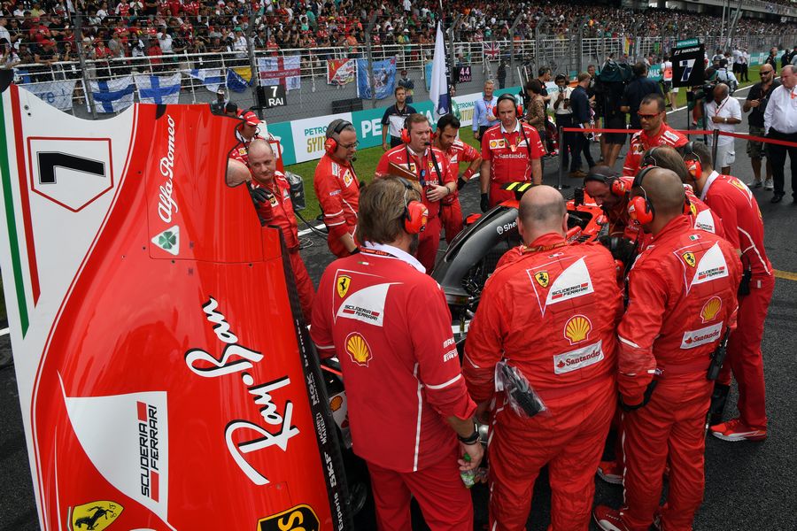 Ferrari mechanics observe the car of Kimi Raikkonen with Turbo issues on the grid