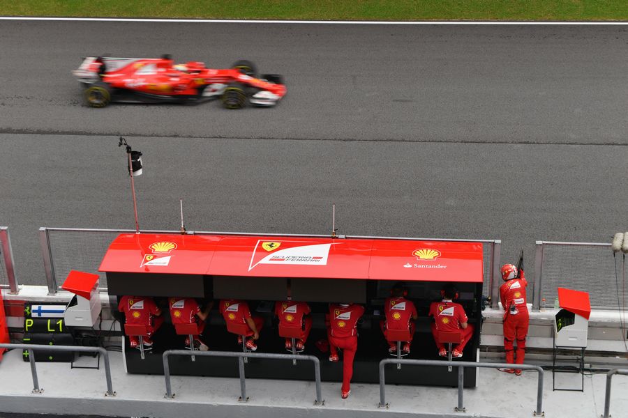 Sebastian Vettel passes the Ferrari pit wall gantry