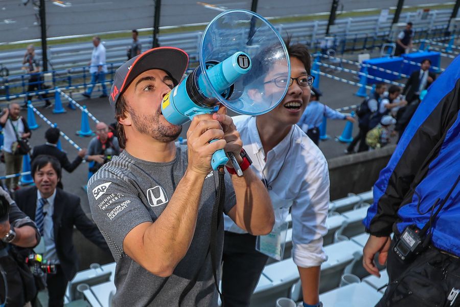 Fernando Alonso talks to the fans using a megaphone
