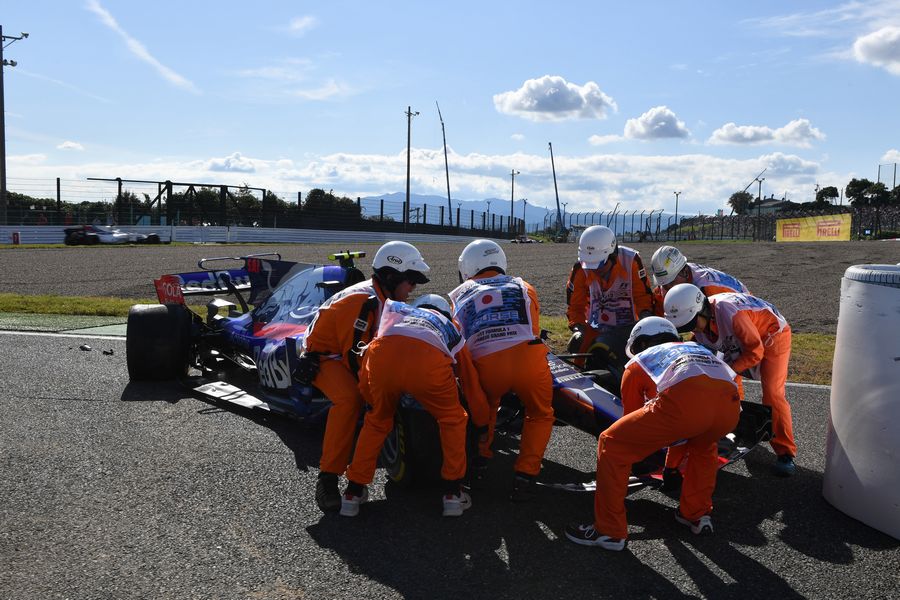 Marshals recover the car of race retiree Carlos Sainz jr in the Toro Rosso