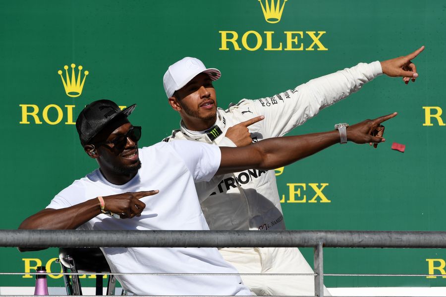 Race winner Lewis Hamilton celebrates on the podium with Usain Bolt