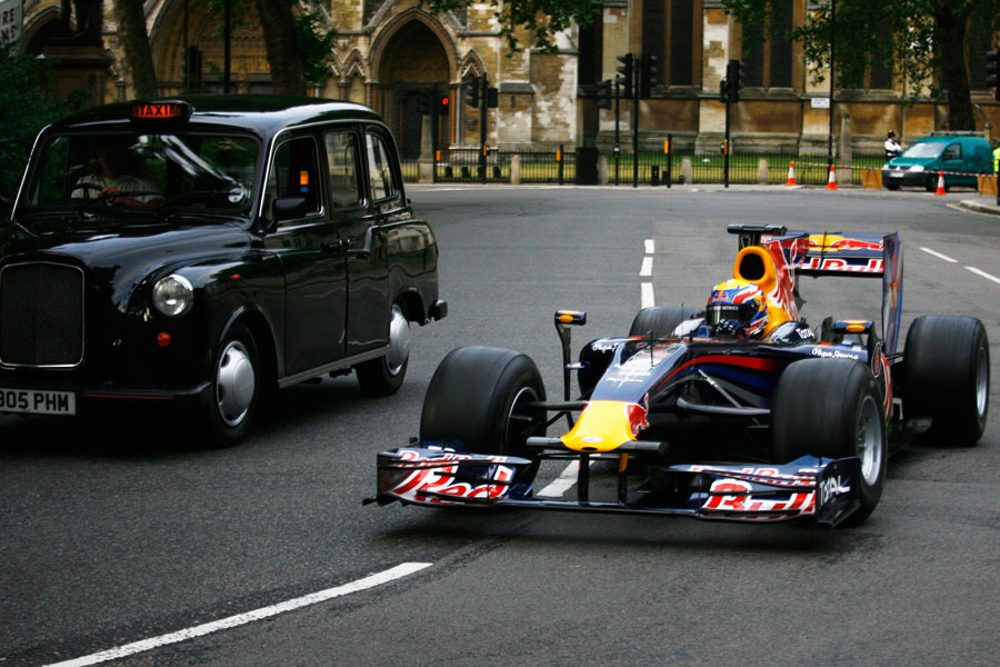 Mark Webber overtakes a black cab outside the Houses of Parliament