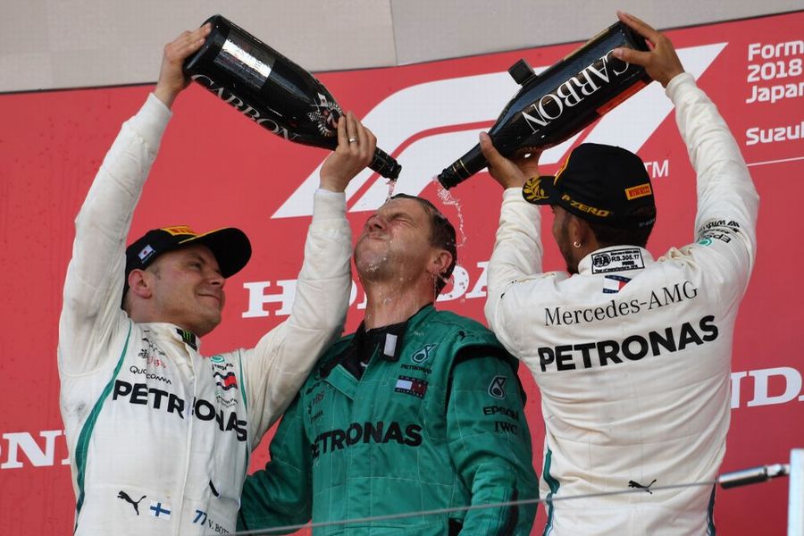 Race winner Lewis Hamilton and Valtteri Bottas pour champagne over a team official as they celebrate on the podium