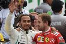 Lewis Hamilton waves at the crowd as he hugs Sebastian Vettel in parc ferme