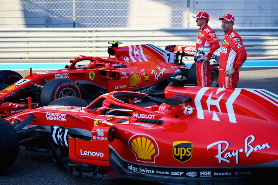 Kimi Raikkonen and Sebastian Vettel pose for a photo with their team in the Pitlane