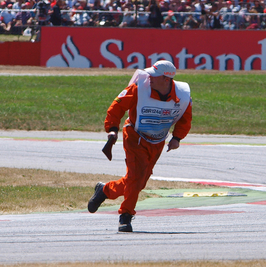 A marshal sprints clear after picking up debris from the track