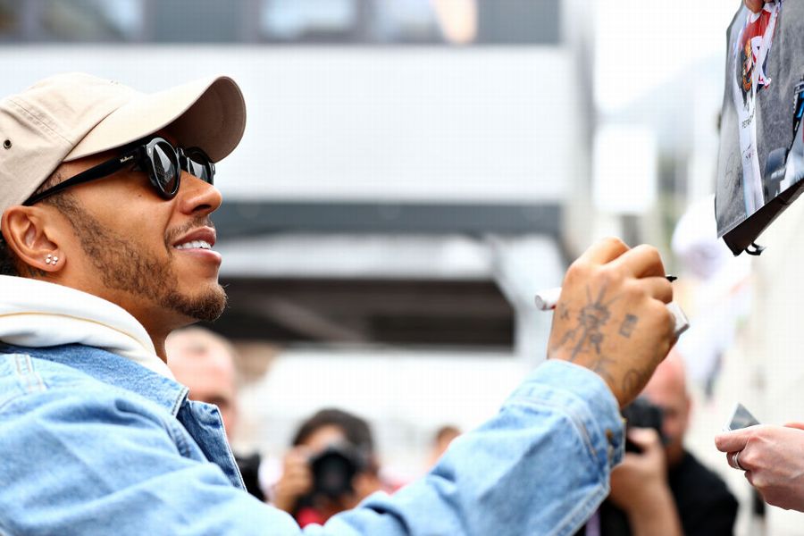 Lewis Hamilton signs autographs for fans in the Paddock