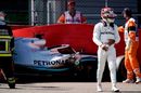 Lewis Hamilton walks next to his damaged car on the circuit after crashing into a wall