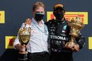 Race winner Lewis Hamilton celebrates with a team member on the podium
