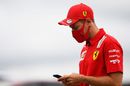 Sebastian Vettel checks his phone in the paddock