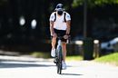 Valtteri Bottas rides a bicycle into the paddock