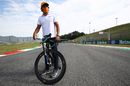 Carlos Sainz Jr rides a bicycle on the track
