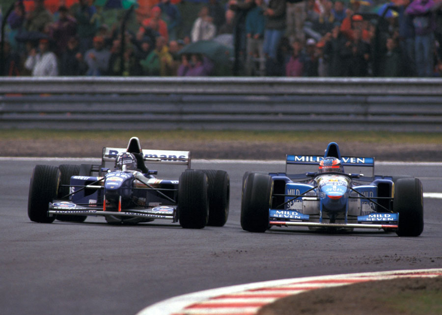 Michael Schumacher (on slicks) holds off Damon Hill in damp conditions