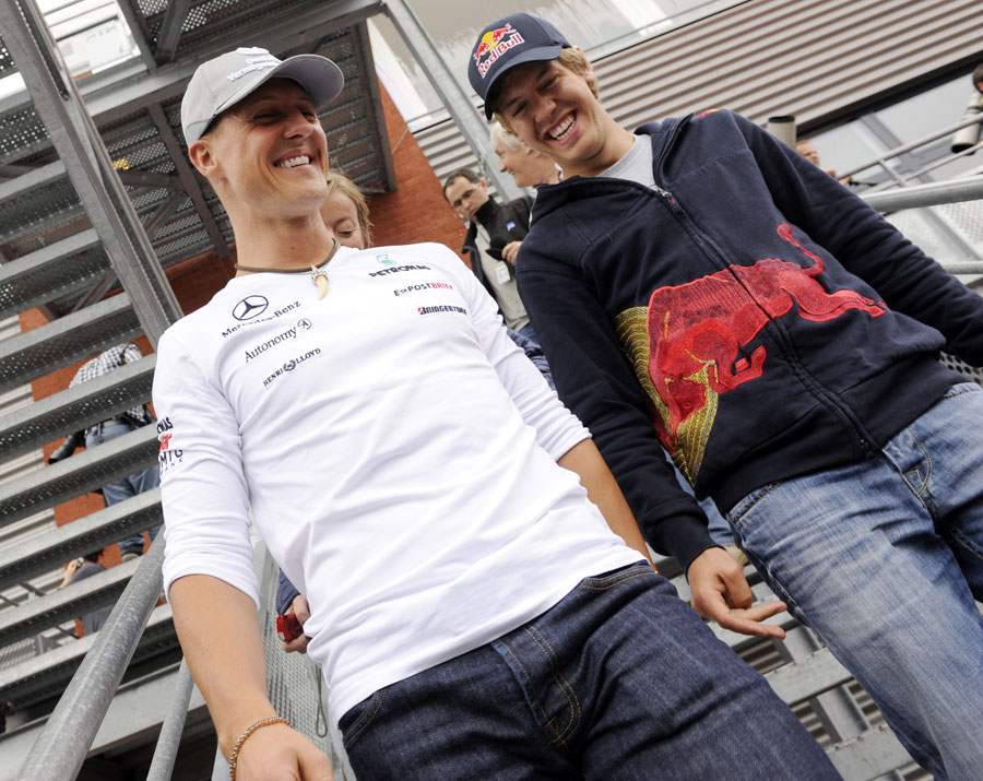 Michael Schumacher and Sebastian Vettel share a joke in the F1 paddock