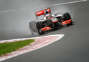 Jenson Button attacks the kerb in the wet