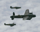 A Lancaster bomber flanked by a Spitfire and a Hurricane flies overhead