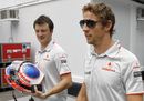 A McLaren team member carries Jenson Button's helmet