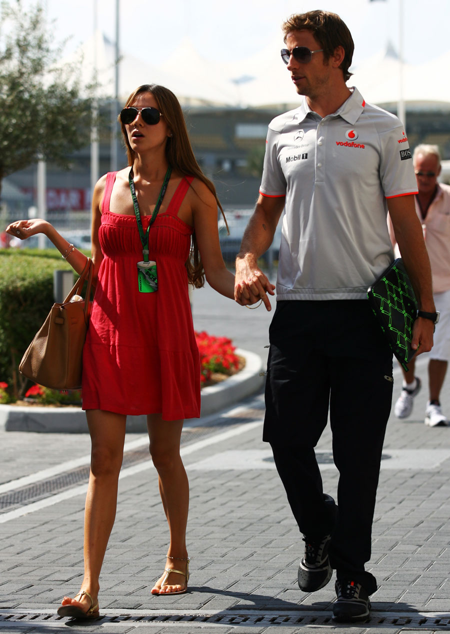 Jessica Michibata leads boyfriend Jenson Button through the paddock
