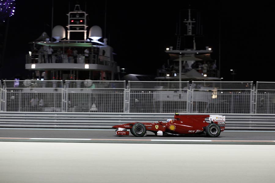 Fernando Alonso drives past the marina at night