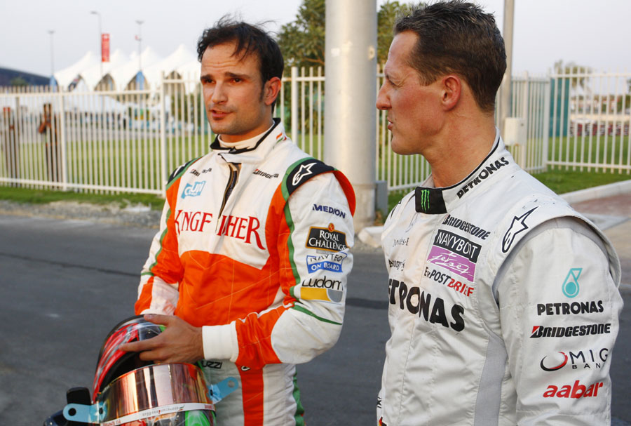 Tonio Liuzzi and Michael Schumacher chat in the paddock after their accidents