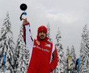 Fernando Alonso throws a ski pole as he poses for a photograph
