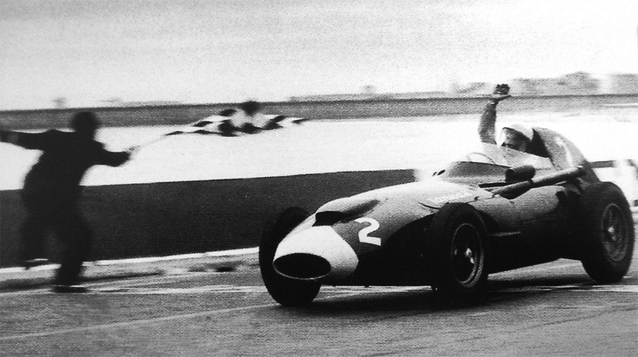 Stirling Moss takes the chequered flag to win the Portuguese Grand Prix