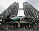 A tourist tries to touch a mock Formula 1 Mercedes at the Malaysian landmark Petronas Twin Towers