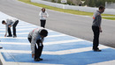 McLaren staff collect tyre marbles off the track