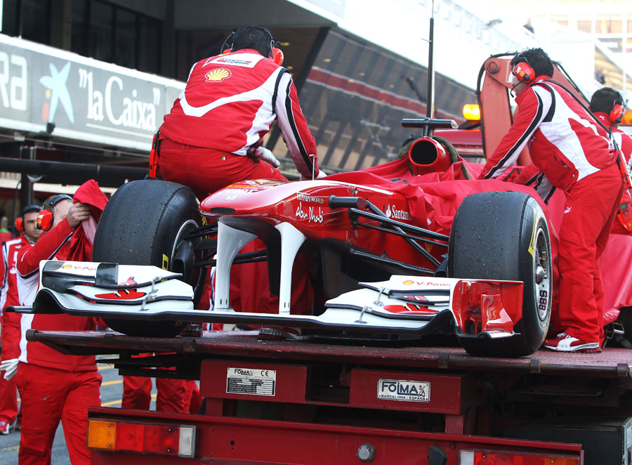 Fernando Alonso's Ferrari is returned to the pits after stopping on track