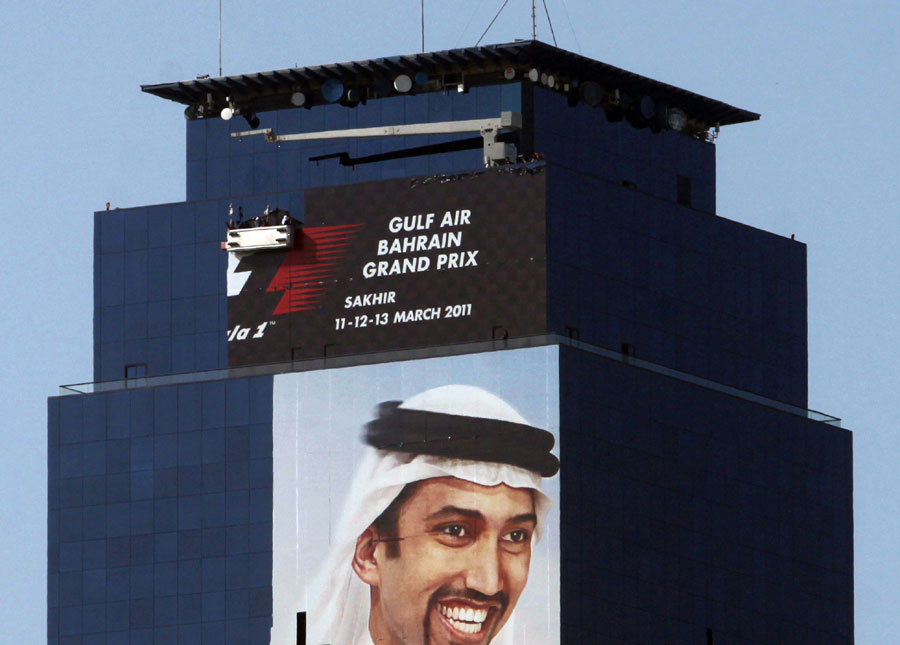 Workers high on an office tower remove a full-length advertisement for the cancelled Bahrain Grand Prix