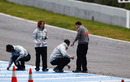 McLaren staff collect tyre marbles off the track