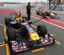 Mark Webber comesinto the pits past a spare Red Bull