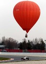 A hot air balloon rises behind Kamui Kobayashi at the Circuit de Catalunya
