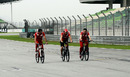 Fernando Alonso cycles round the track partnered by team members