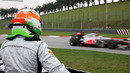 A sidelined Narain Karthikeyan watches Lewis Hamilton pass by