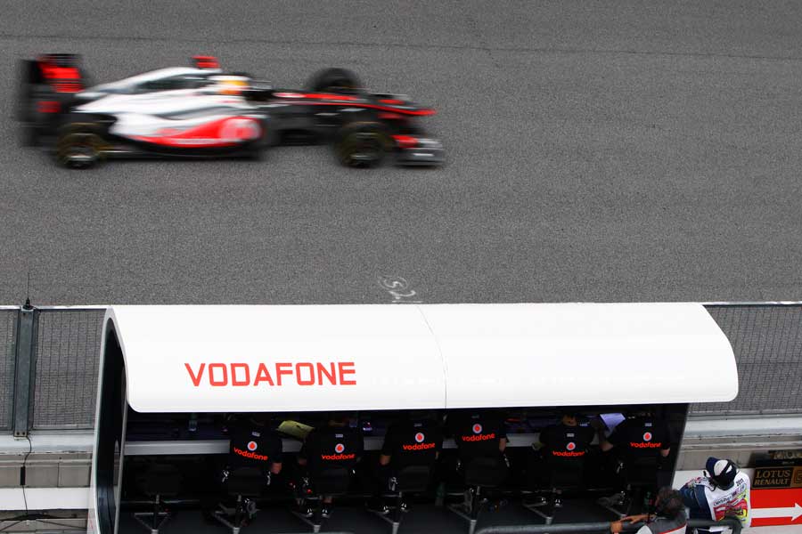 Lewis Hamilton speeds past the McLaren pit wall