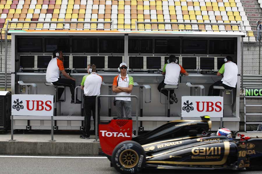 Adrian Sutil watches on as Vitaly Petrov leaves the pit lane
