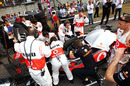 McLaren mechanics work on Lewis Hamilton's car on the grid