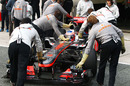 Jenson Button is wheeled back in to the garage