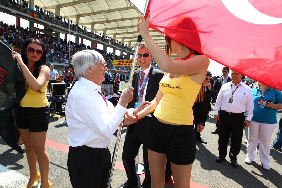 Bernie Ecclestone takes the Turkish falg off a grid girl for the start of the national anthem