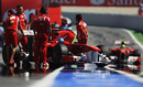 Fernando Alonso is wheeled back into his garage as Felipe Massa comes down the pit lane